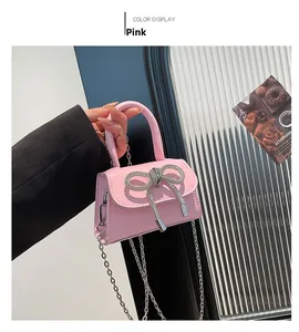 Detailed view of pink mini crossbody bag with a large rhinestone bow and silver chain