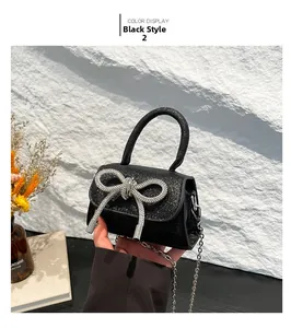 Detail of black sequin mini bag with large silver rhinestone bow and metal chain