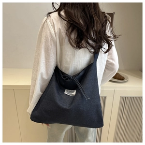 Nahaufnahme der dunkelblauen Canvas-Tasche mit Modelabel und Kordelzug-Detail