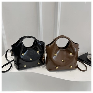 Detail of glossy black and brown handbags with gold dog paw and bone metal charms