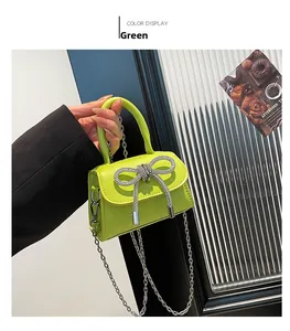 Detail of lime green mini bag with rhinestone bow and silver chain strap