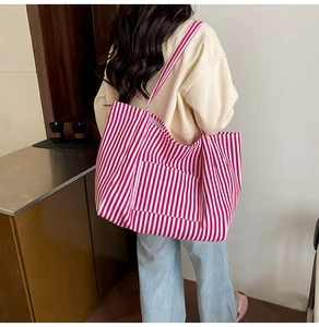 Detailed view of large red and white striped canvas tote bag worn by a model in casual setting