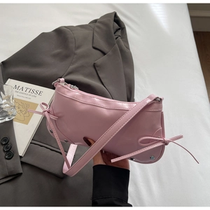 Close-up of pink patent leather shoulder bag with bow details and silver rivets