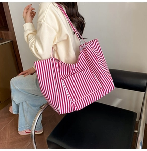 Close-up of a large red and white striped canvas tote bag worn on shoulder for daily use