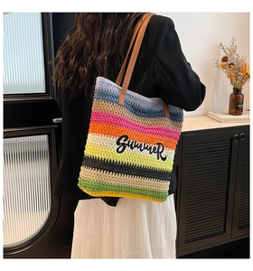 Detail of colorful striped straw tote bag featuring Summer embroidery and leather handles