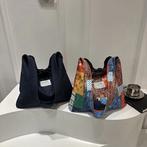 Große florale Canvas-Tragetasche und solide Denim-Schultertasche auf minimalistischem Ständer