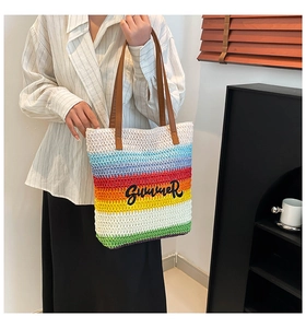 Detail of rainbow striped straw tote bag with black SUMMER embroidery and brown PU handles