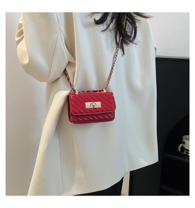 Detalle de mini bolso bandolera acolchado rojo con cierre giratorio dorado