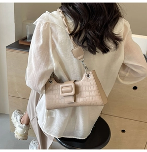 Detail of beige crocodile pattern baguette bag with large square buckle and chain strap