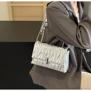 Gros plan sur un sac argenté matelassé avec bandoulière en chaîne et fermoir chic