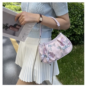 Detail of light purple bag with floral embroidery, metal chain and bead tassels