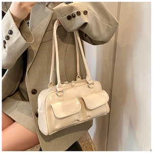 Detail view of cream underarm bag with double front flap pockets and glossy finish