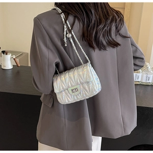 Sac bandoulière matelassé laser argenté avec chaîne, porté sur un blazer marron chic