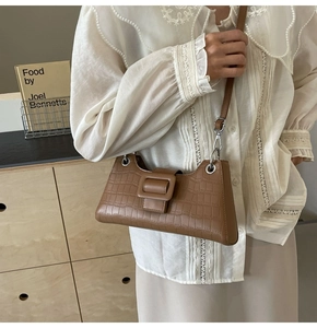 Close-up of brown crocodile texture on a French style baguette bag with metal buckle