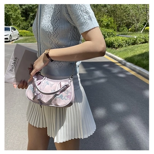 Outdoor shot of a light purple floral embroidery saddle bag with a metal chain strap