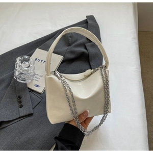 Detail of cream white faux leather shoulder bag with silver chain on grey blazer