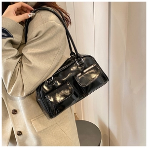 Detail of black patent leather underarm bag with double pockets and silver buckles