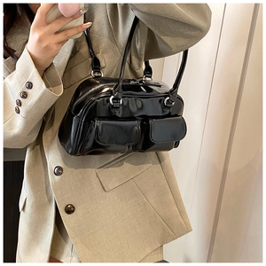 Detail of glossy black underarm bag with double front pockets on female model