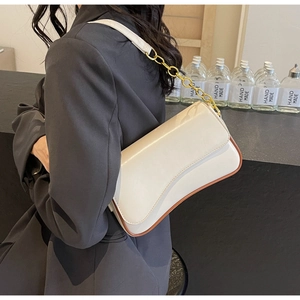 Detailansicht der cremeweißen Achseltasche mit Goldkette und braunem Rand-Finish