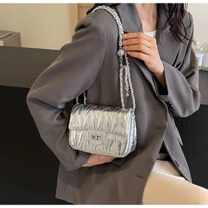 Sac à bandoulière argenté métallisé plissé porté avec un blazer gris chic et moderne
