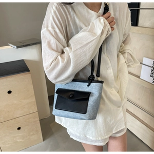 Détail du sac seau en feutre gris avec poche en cuir noir et fine bandoulière