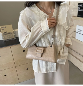 Detail showing beige crocodile embossed leather and elegant square buckle of the baguette bag