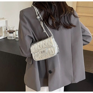Petit sac bandoulière argenté matelassé avec chaîne porté sur un blazer gris
