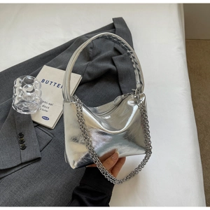 Close-up of metallic silver underarm bag with leather handle and metal chain detail