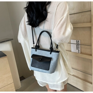 Détail du sac cabas bleu clair texturé avec poche en cuir noir et poignée à nœuds élégante