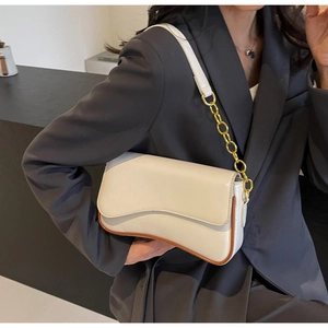 Detail der cremefarbenen Baguette-Tasche mit Wellenklappe und goldener Kettenriemen