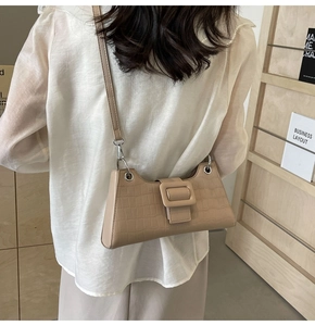 Detail shot of beige baguette bag with crocodile texture and metal eyelet accents