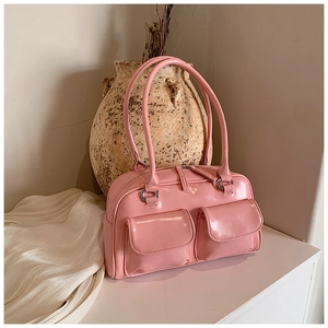 Detailed close-up of glossy pink patent leather underarm bag with double front pockets