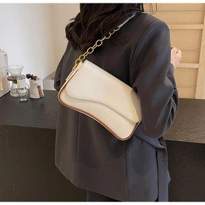Detail einer cremeweißen Baguette-Tasche mit braunen Kanten und goldener Kette