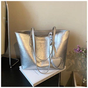 Detailansicht der silbernen Tragetasche mit Crinkle-Metallic-Textur und Herzanhänger