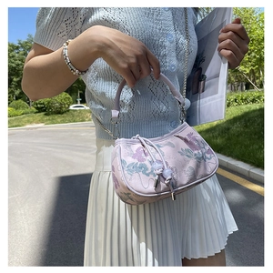 Detail view of light purple jacquard handbag with floral patterns and pearl tassel charm