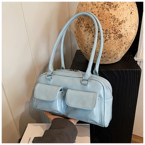 Detail of light blue glossy patent leather shoulder bag with two front pockets