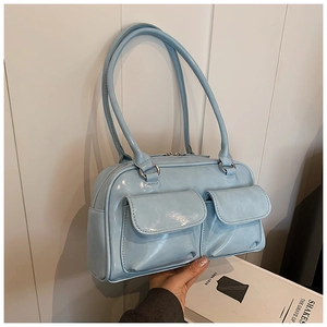 Detail of light blue glossy patent leather handbag with dual front pockets and silver hardware