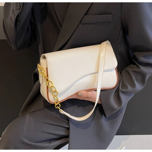 Detailansicht der weißen Satteltasche mit braunem Rand und auffälliger goldener Kette