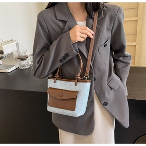 Détail du petit sac seau en toile et cuir avec texture denim bleu et rabat de poche marron