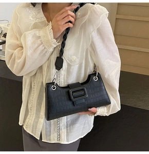 Detail of black faux crocodile skin shoulder bag with chunky woven strap and square buckle