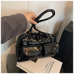 Close-up of black glossy patent leather shoulder bag with silver D-ring hardware