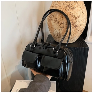 Detail of glossy black underarm bag with double front pockets and smooth leather texture