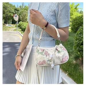 Detail of embroidered floral crossbody bag with white beaded drawstring and silver chain