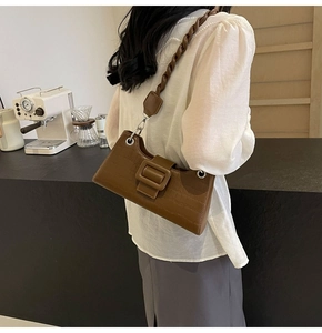 Chic brown crocodile pattern baguette bag with braided strap shown in a cafe setting