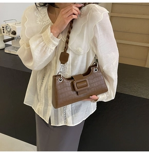 Close-up of dark brown crocodile pattern bag with braided strap and large buckle