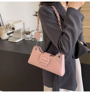 Close-up of pink baguette bag with crocodile texture and braided shoulder strap