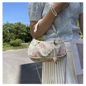 Detail of floral and crane embroidery on a beige textured handbag with chain