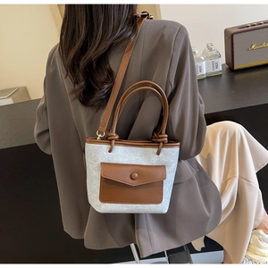 Détail du sac seau bicolore avec garniture en cuir marron et texture denim gris