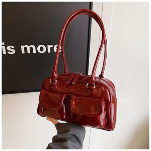 Close-up of burgundy patent leather underarm bag with two symmetrical front pockets