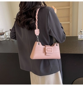 Pink faux crocodile leather baguette bag featuring a woven strap and square buckle detail